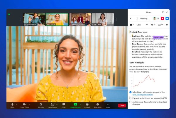 A woman smiling while engaged in a video call with her colleagues and managing a project