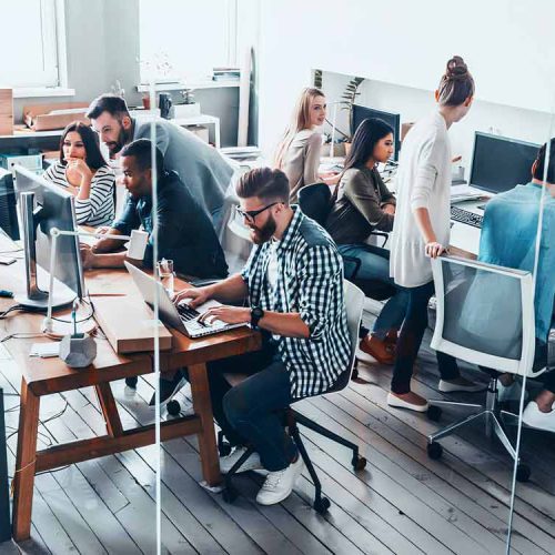 A diverse team collaborating in a modern office environment, engaged in professional tasks and discussions.